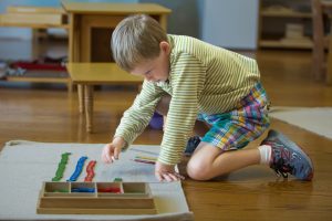 Boy playing stamp game in a Montessori classroom